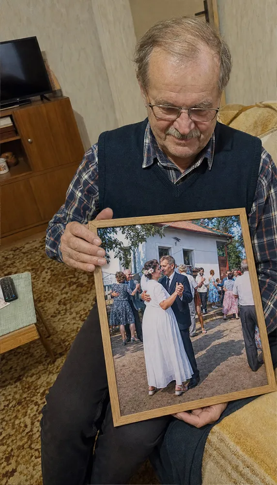 Starší muž drží zarámovanou svatební fotografii