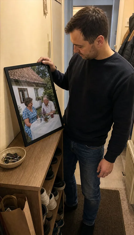 Muž si prohlíží zarámovanou fotografii prarodičů v chodbě